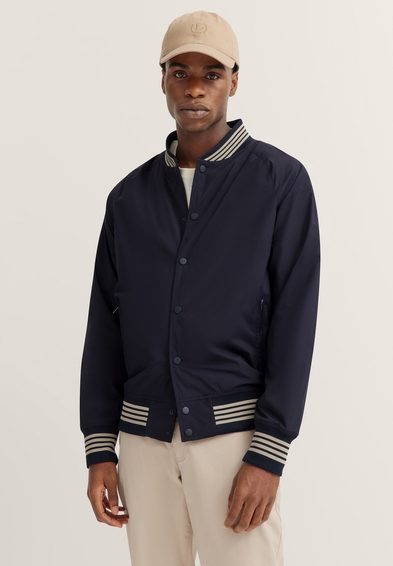 Marineblaue Bomberjacke mit gerippten gestreiften Ärmeln und Saum, mit Druckknopfvorderseite und seitlichen Taschen, aus glattem Stoff gefertigt.