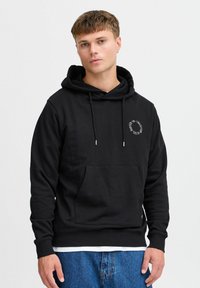 Felpa nera in cotone con tasca frontale, cappuccio con coulisse regolabile e accento con logo circolare. Presenta polsini e orlo a coste, con una vestibilità morbida.