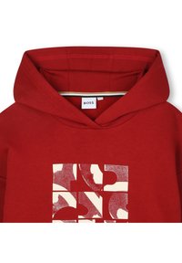 Rød hettegenser med et stort grafisk design i krem og mørk burgunder på forsiden, med snor i hetten og myk tekstur.