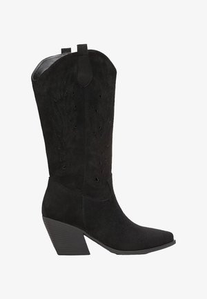 Bottes de cowboy en daim noir avec un bout pointu, hauteur mi-mollet, des motifs découpés et un talon en bloc texturé.