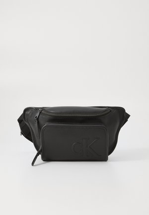 Borsetă din piele neagră cu un compartiment principal cu fermoar, buzunar frontal, logo-ul „cK” embosat și curea ajustabilă. Textură netedă și design elegant.