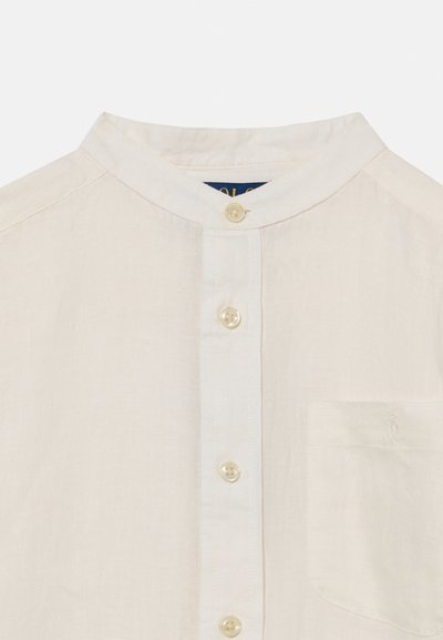 Λευκό λινό πουκάμισο με γιακά μπαντάνα, κουμπιά στο μπροστινό μέρος και τσέπη στο στήθος με διακριτικό κεντημένο λογότυπο.