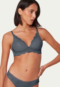 Szary biustonosz z koronkowym wykończeniem, z regulowanymi ramiączkami. Posiada gładką bazę z materiału oraz dekoracyjne koronkowe akcenty wzdłuż krawędzi.