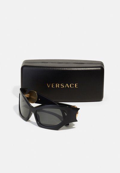 Čierne slnečné okuliare v podobe mačacích očí s tmavými šošovkami, zlatými akcentmi a lesklým čiernym puzdrom so zlatým nápisom "VERSACE".