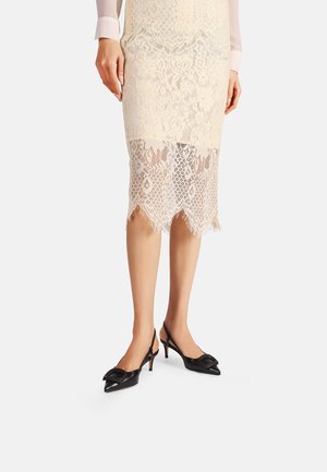 Tacchi slingback neri con punta affilata, realizzati in pelle liscia. Presentano una fibbia decorativa sulla tomaia e tacchi a spillo sottili.