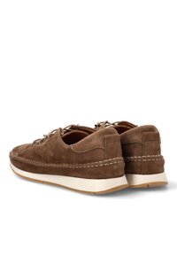 Zapatos de ante marrón con un diseño de perfil bajo, que cuentan con una suela de goma blanca y costuras decorativas a lo largo de los bordes.