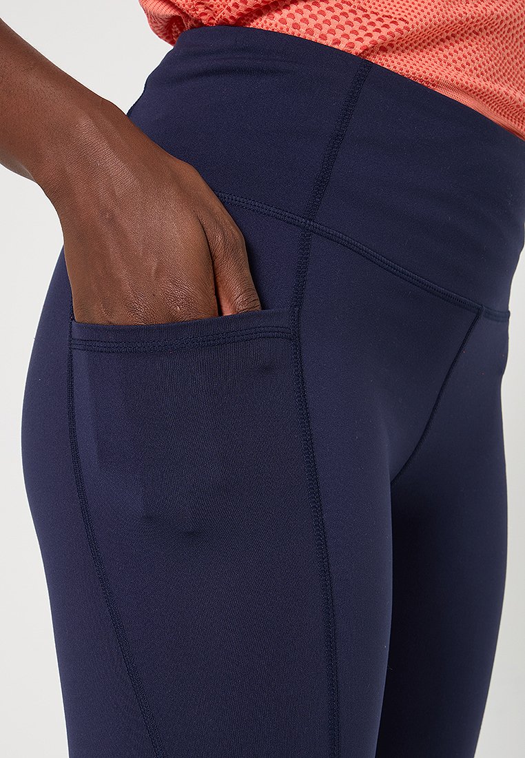 Granatowe legginsy z boczną kieszonką, wykonane z elastycznego materiału o gładkiej teksturze i płaskich szwach dla zwiększonego komfortu.