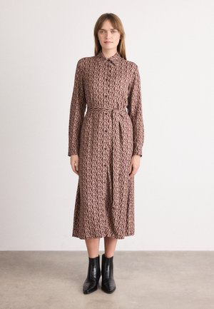 Langermet, knappe-opp kjole i en mauve stoff med et G-mønster. Har en belted midje og faller under knærne. Kombinert med svarte ankelstøvler.