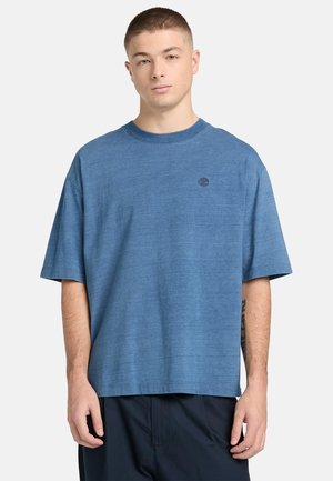 Niebieska koszulka z krótkim rękawem wykonana z fakturowanej tkaniny, z okrągłym dekoltem i małym logo na piersi. Luźny krój.