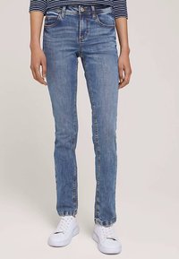 Blugi din denim albastru deschis, cu croială strâmtă, cinci buzunare și textură ușor decolorată. Asortați cu adidași albi.