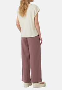 Crème kleurig T-shirt met korte mouwen gecombineerd met losse, gestructureerde mauve wijde broek en beige platform sandalen. Eenvoudig en schoon ontwerp.