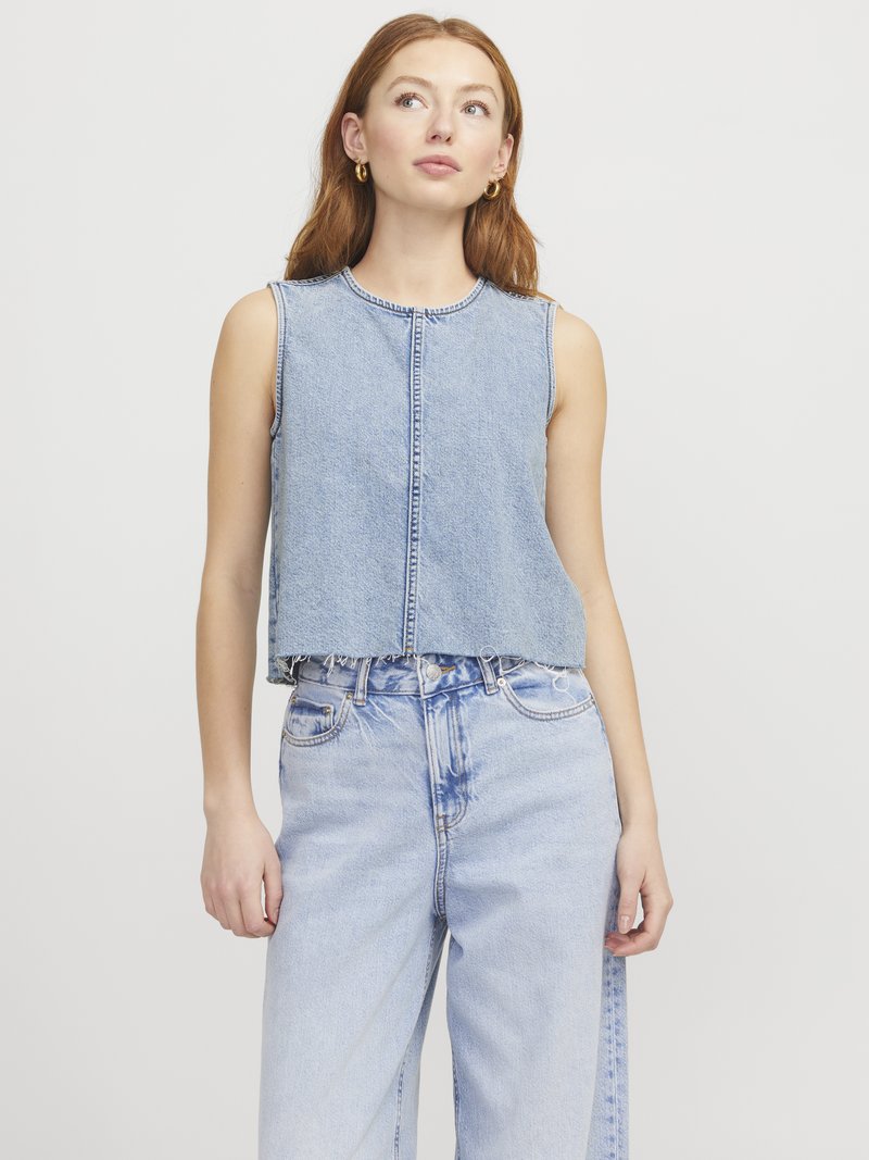 Top in denim senza maniche e cropped di colore azzurro con cuciture visibili, scollatura rotonda e orlo grezzo; abbinato a jeans blu chiaro con vestibilità ampia.