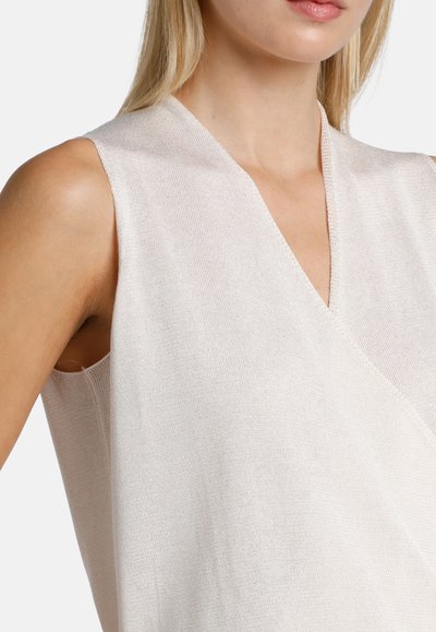 Top sin mangas de un tono beige pálido con un profundo escote en V, textura acanalada y un corte relajado, con una silueta ligeramente holgada.