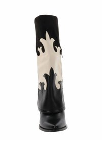 Bota de cuero negra y blanca a media pantorrilla con patrones decorativos parecidos a llamas y punta redonda sobre un fondo blanco.