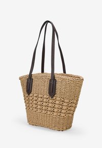 Bolso de tote de paja trenzada con una forma estructurada, asas de cuero marrón y un cuerpo texturizado que presenta una sección inferior con un patrón.