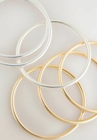 Kolm ringkõrvarõngast hõbedaste ja kuldsete toonide kombinatsioonis, millel on siledad metallasjad ja ümmargune kuju, millel on poleeritud viimistlus.