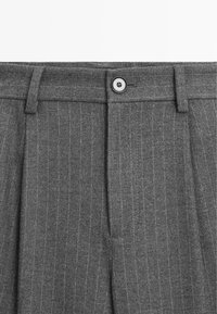 Grijze wollen broek met een streeppatroon, geplooid ontwerp, riemlussen, enkele knoopsluiting en een gladde textuur.