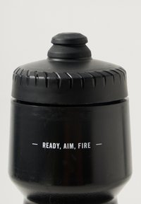 Bouteille noire avec un bouchon texturé, présentant un bord surélevé et strié. Le texte indique "PRÊT, VISEZ, TIREZ" en blanc à l'avant.