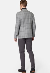 Szary blazer w kratę o dopasowanym kroju, z czarnym akcentem kołnierza, w połączeniu z szarymi spodniami i czarnymi botkami za kostkę. Charakteryzuje się gładką fakturą.