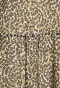 Mönstrad tyg i nyanser av beige, brunt och svart, med en textur skapad av penseldrag-liknande mönster och subtila veck.