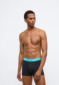 Boxers noirs en coton avec une ceinture de logo Nike turquoise ; texture douce et design ajusté.
