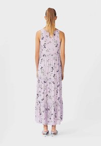 Lila maxi-jurk met een bloemenpatroon, mouwloos ontwerp en tiered ruffles aan de zoom. Zachte stof, losse pasvorm en enkel lengte.