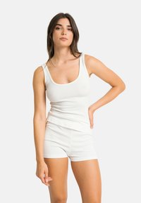 Ensemble débardeur et short à rayures blanches, avec un décolleté arrondi et une coupe ajustée. Le tissu semble doux et légèrement texturé.