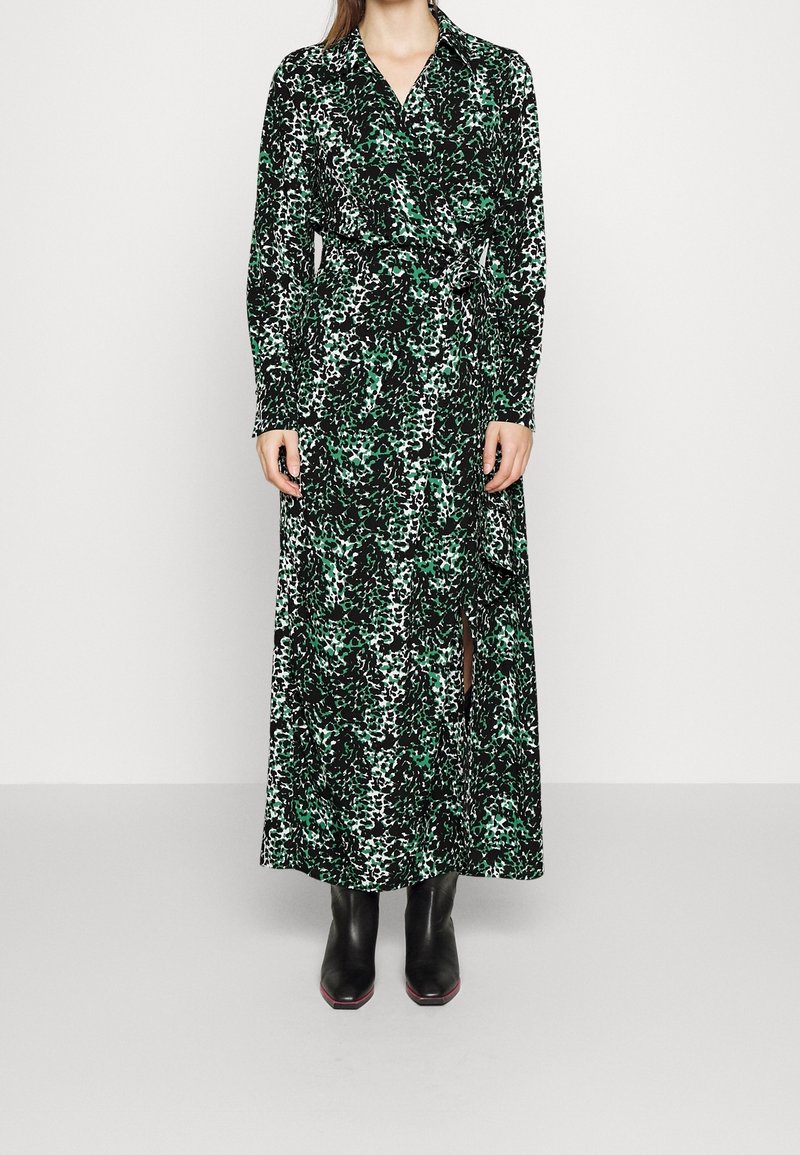 Långärmad omlottklänning i svart och grön leopardmönster, med något definierad midja och en sidoklyvning. Matchas med svarta stövlar.
