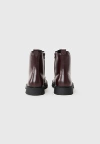Botas de tobillo de cuero burdeos con un acabado suave, que cuentan con un cierre lateral y una suela de goma negra gruesa para mayor durabilidad y estilo.