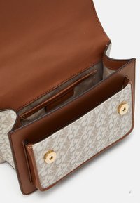 Borsa a tracolla in pelle marrone con una parte frontale in tessuto bianco a fantasia, dotata di chiusura a scatto e di un dettaglio a bottone in tonalità oro all'interno. L'interno include una tasca.