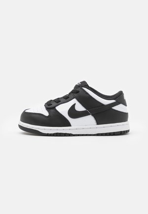 Sapatilha Nike em preto e branco com uma parte superior de couro liso, biqueira perfurada, colarinho acolchoado e sola de borracha com um piso texturizado.