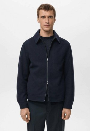 Giacca blu navy con cerniera e colletto, realizzata in tessuto strutturato. Presenta un taglio diritto e due tasche frontali.