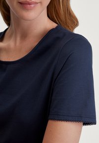 Navyblauw top met korte mouwen van zachte stof, met een ronde halslijn en delicate kantversiering op de mouwen, zachte textuur.