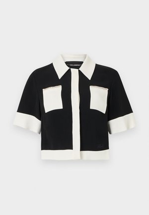 Črno-bela srajca s kratkimi rokavi in ovratnikom, z dvema našitim žepoma, zapenjanjem na gumbe spredaj ter gladkim, lahkim materialom.