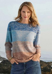 Maglione lavorato a maglia in gradiente blu e beige, con maniche lunghe e colletto a girocollo. Tessuto morbido con vestibilità rilassata. Indossato con jeans in denim.