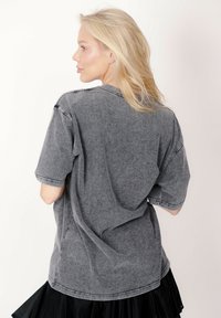 Szara, oversize'owa koszulka z krótkimi rękawami. Wykonana z miękkiego materiału, o luźnym kroju, z widocznymi przeszyciami.