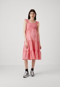 Rožinė sluoksniuota suknelė su frill apykaklėmis ir smock bodice. Medžiaga atrodo minkšta; iki vidurio blauzdos ilgis su laisvu siluetu. Kasdieniai avalynė.