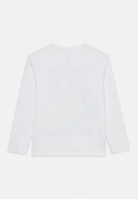 White long-sleeve crew neck shirt laid flat, seen from the back, with a faint, colorful graphic visible through the fabric.