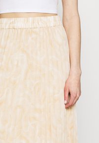 Plisserad kjol i mjukt, ljusgult tyg med ett subtilt mönster. Har en elastisk midjeresår och en lätt, flytande design.