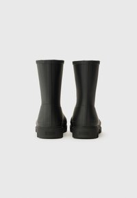 Black rubber ankle boots with a smooth finish, rounded tops, and textured side panels. Features a flat sole and brand logo on the back.