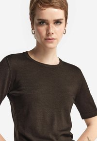 Mørkebrun kortærmet t-shirt med rund halsudskæring, blød tekstur og sømløst design. Har subtile syninger som detalje.