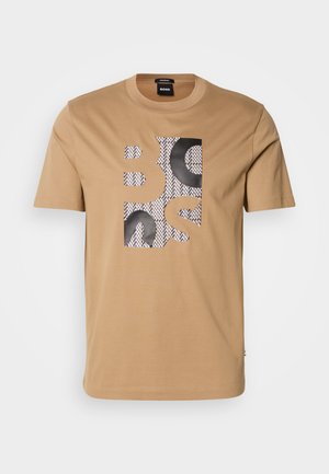 T-shirt beige a maniche corte con lettere a blocchi nere e bianche che formano la parola "BOSS" sul davanti.