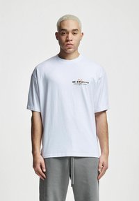 Tricou alb din bumbac cu mâneci scurte, având un mic logo multicolor pe pieptul stâng. Croi lejer și textură moale.