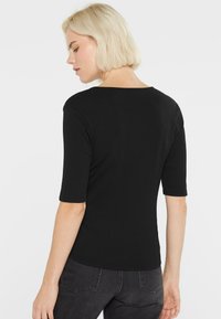 Schwarzes, figurbetontes Top mit rundem Ausschnitt und kurzen Ärmeln. Der glatte Stoff und die gerippte Textur sorgen für Komfort und Stil.