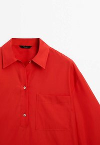 Camicia rossa a maniche lunghe con colletto button-down, una tasca sul petto e tessuto liscio. Presenta due bottoni sotto il colletto.