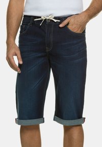 Pantalones cortos de mezclilla azul oscuro con dobladillo doblado, con un cordón ligero y detalles de costura visibles. Color sólido sin patrones.