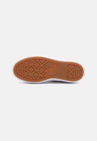 Semelle de sneaker en caoutchouc avec un motif texturé marron et des bordures blanches. Présente des designs géométriques pour une meilleure traction.