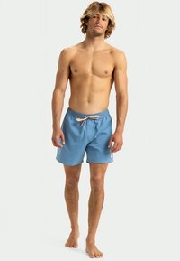 Vyrų maudymosi šortai, šviesiai mėlynos spalvos audinys, elastinė juosta su raišteliu, šoninės kišenės ir paprastas dizainas. Be raštų ar puošybos.