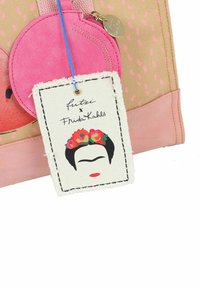 Roze stoffen tote bag met een stippenontwerp, voorzien van een klein roze ritszakje en een label met een afbeelding van Frida Kahlo en een kleurrijke bloemenkrans.