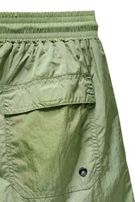 Lysgrønne shorts lavet af skinnende, letvægtsstof. Har en elastisk talje og en lomme med en cirkulær logo detalje.